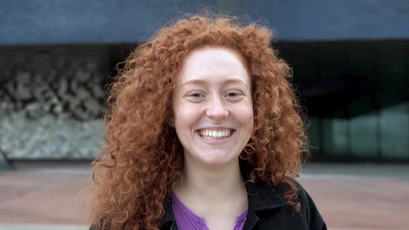 Beautiful young woman with orange hair smiling in front of camera