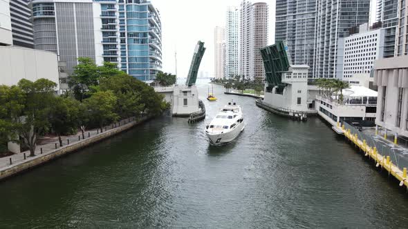 beautiful aerial of a luxury yacht navigating the downtown Miami River under the Brickell Avenue Bri