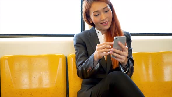 Young Asian Business Woman Using a Mobile Phone and Get Surprise Good News on the Train Inside