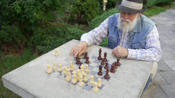 Zoom Out Concentrated Elderly Man Makes Chess Move