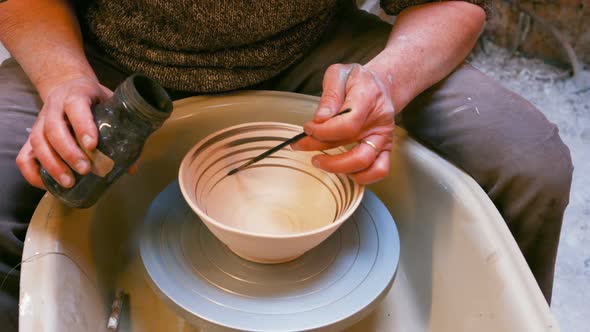 Male artist painting on earthenware bowl