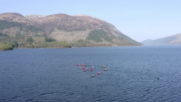 Aerial View of Canoeists in a Lake Surrounded by Mountains and Nature