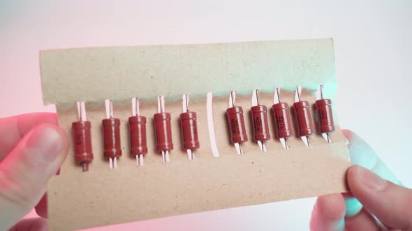 Old Orange Resistors Close Up in a Paper Package in Hands on a White Background Closeup in Colored
