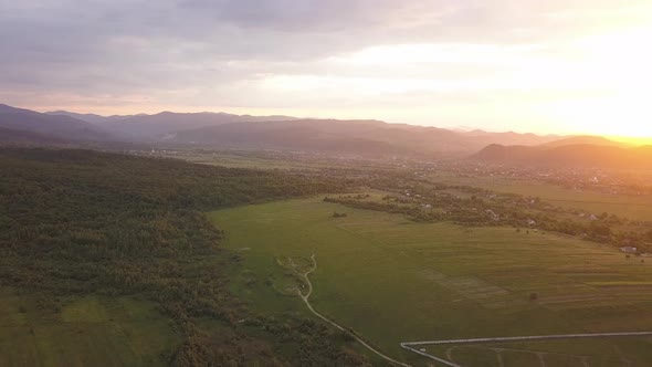 Aerial view of Nadvirna town with scattered small houses on green hills and distant Carpathian