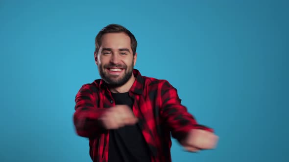 Man with Beard Having Fun, Smiling, Dancing in Studio Against Blue Background. Music, Dance Concept