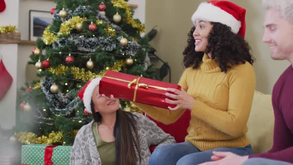 Happy diverse group of friends sharing with presents at christmas time
