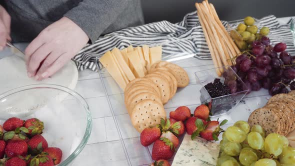 Step by step. Arranging cheese platter with fresh fruits, gourmet cheese, and crackers
