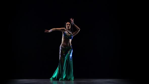 Girl Performs in a Dark Studio Belly Dance. Black Background. Slow Motion