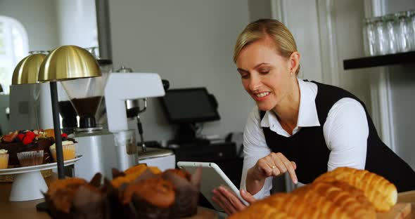 Smiling waitress using digital tablet at counter