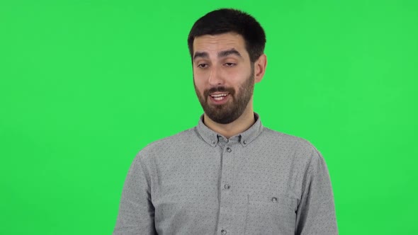 Portrait of Brunette Guy Is Talking and Pointing Side Hand for Something, Copy Space. Green Screen