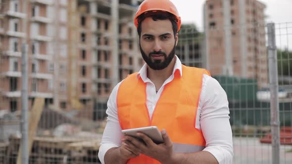 Portrait of Construction Worker on Building Site with Tablet Looking at the Camera Professions