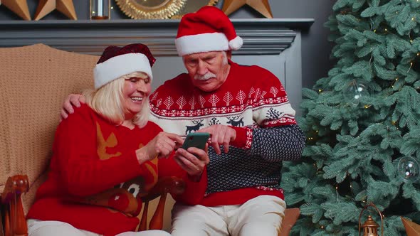 Senior Family Couple Searching Purchase Online Christmas Gifts in Mobile Phone Application at Home