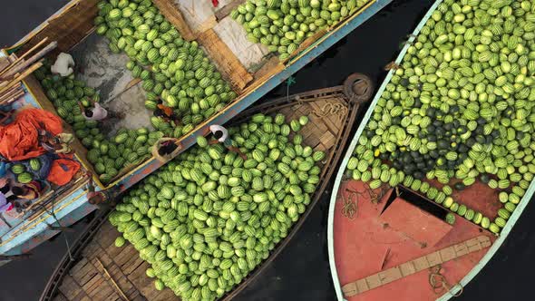 Aerial view of workers exchanging watermelons on boats along the Buriganga River.