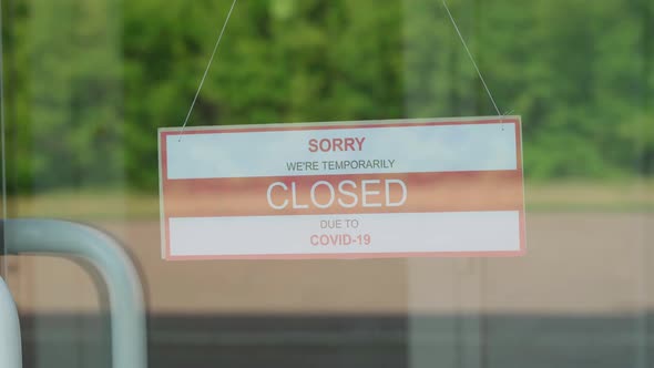 A Man Removes a Sign That Read CLOSED During the COVID19 Pandemic That Hung on a Transparent Door or