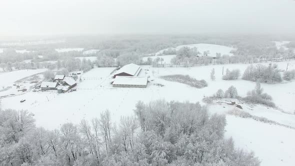 Aerial: Snow-covered stud farm in the wintertime