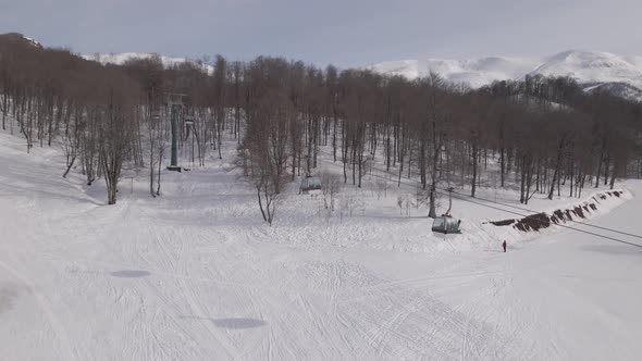 Flying over rope-way with gondolas at mountain resort Crystal Park in Bakuriani. Snowy winter day.