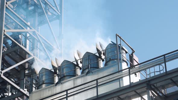 Intense white smoke from the company's chimneys. Metal structures of the plant