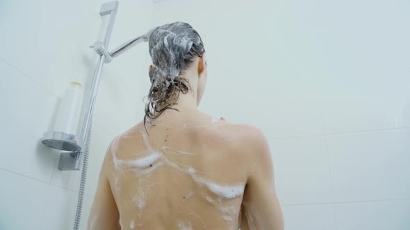 Woman Washing Body and Black Hair with Shampoo in Shower