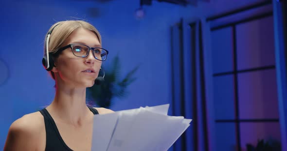 Woman in Sportswear in Headset which Talking with Interlocutor Through Mic During Review Documents