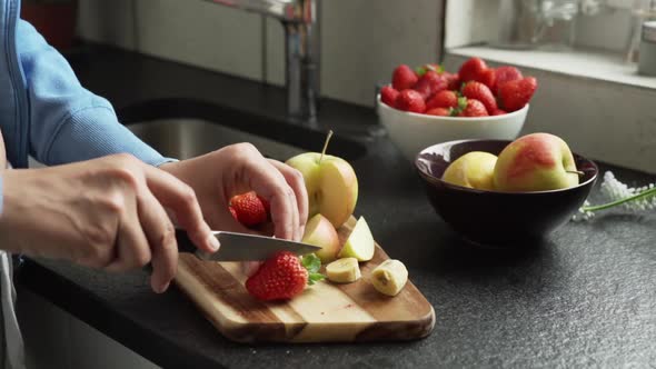 Woman cutting fresh fruit in the kitchen