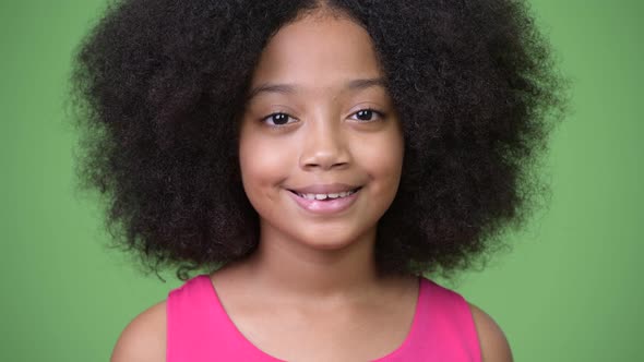 Young Cute African Girl with Afro Hair Smiling Against Green Background