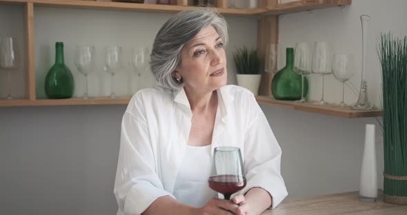 Portrait of a Happy Senior Elderly Woman with Glass of Wine in a Bright Comfortable Apartment