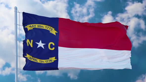 North Carolina Flag on a Flagpole Waving in the Wind Blue Sky Background