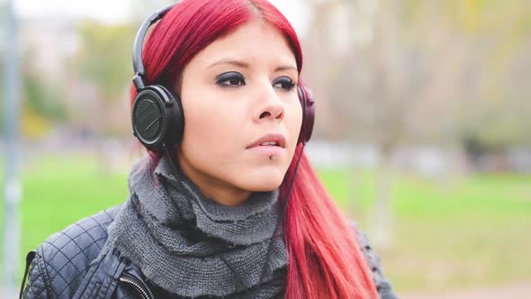 Young handsome  redhead girl listening to music in the city park