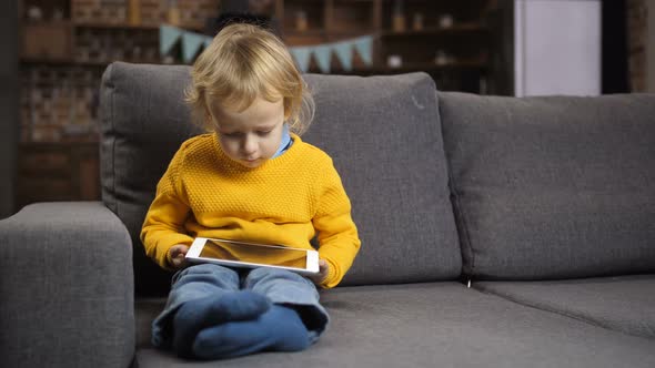 Cute Blond Toddler Boy Using Touchpad on Sofa