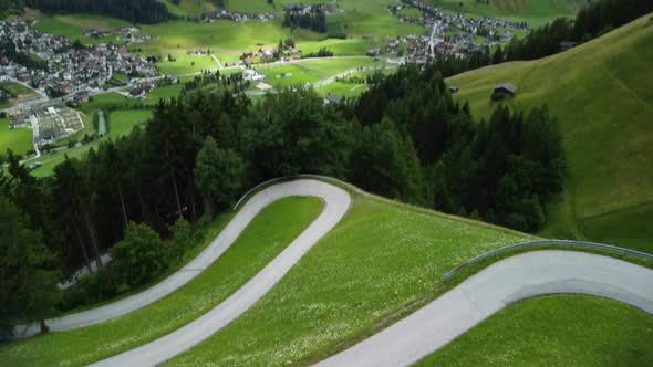 Aerial view while a drone launch from a meadow with a curvy street and high mountains in the backgro