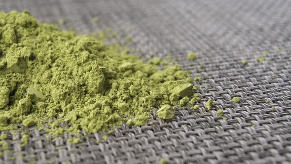 Green powdered Chinese traditional matcha tea on a gray plastic mat