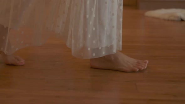 A Woman Walks Barefoot on the Parquet in a Sunny Room