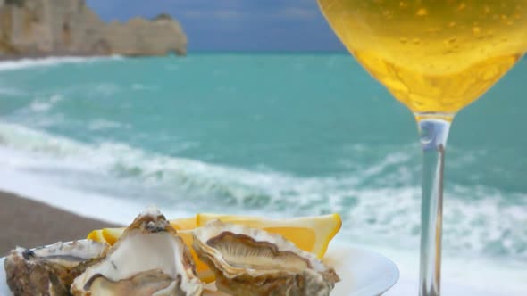 Wine Is Poured in Glass Against Plate with Oysters