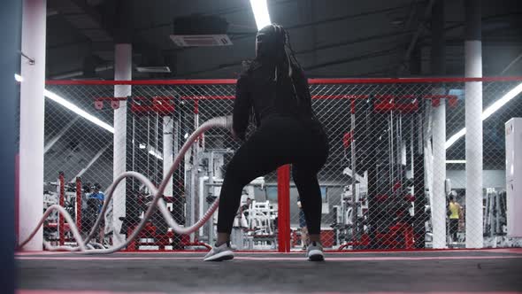 An Africanamerican Doing Exercises with Her Hands Using Ropes  Rope Crossfit