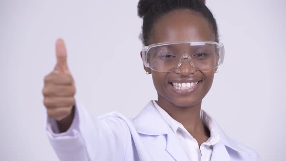 Face of Young Happy African Woman Doctor with Protective Glasses Giving Thumbs Up