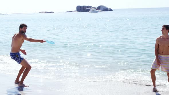 Friends playing frisbee at beach