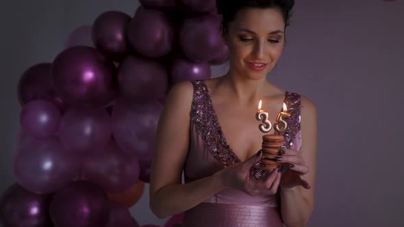 Young Woman in Purple Dress Blowing Out Candles