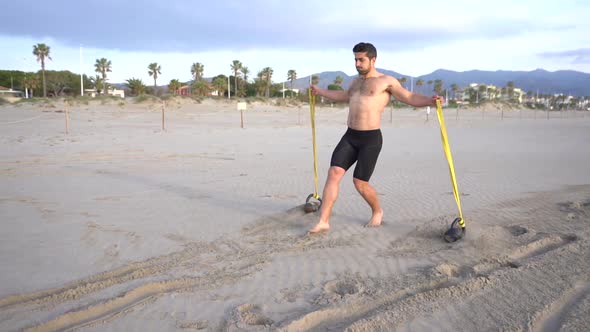 metabolic workout on the beach with muscular man performing back and rubber variant with kettlebell