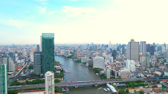 Aerial view flight over moving sky train on a bridge over the Chao Phraya River