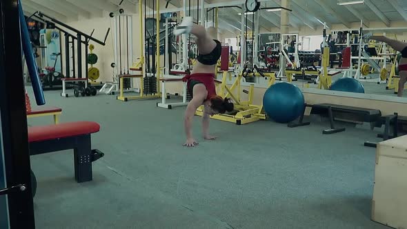 Young Athletic Girl Stands on Her Hands Performing an Acrobatic Stunt