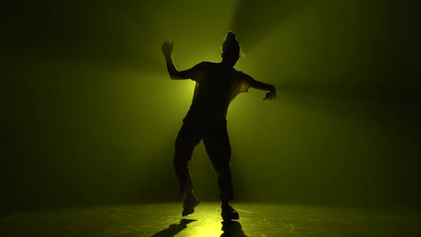 Silhouette Young Hip-hop Dancer, Dancing in Dark Studio in the Green and Yellow Fog. Hip Hop Culture