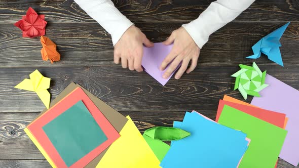 Man Folding Paper To Make Origami.