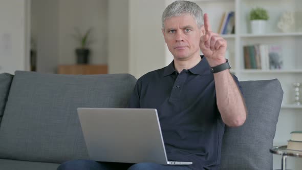 Focused Middle Aged Businessman with Laptop Pointing with Finger 