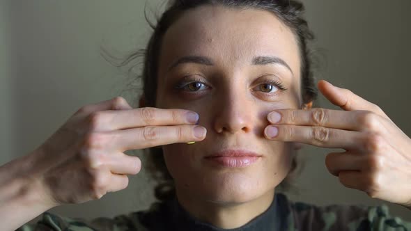 Young Girl is Paining Blue and Yellow Ukrainian Flag on Her Cheek Using Her Fingers Wearing Military