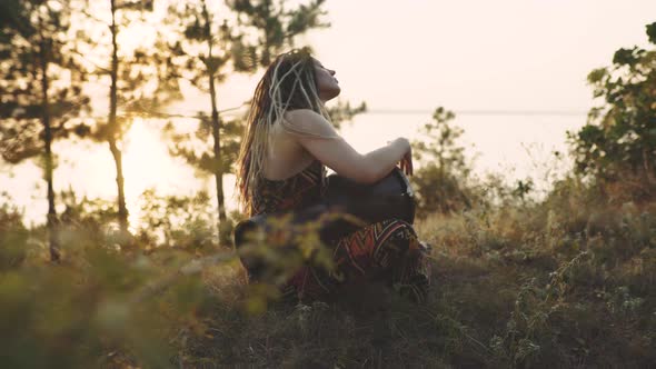 Beautiful Young Hippie Woman with Dreadlocks Playing on Djembe