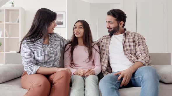 Happy Family of Parents and Daughter Sitting on Sofa at Home in Living Room