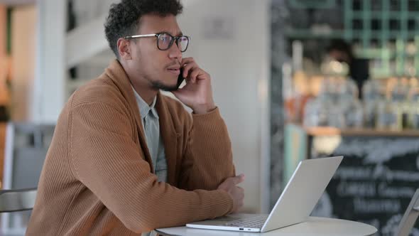 African Man Laptop Talking Smartphone