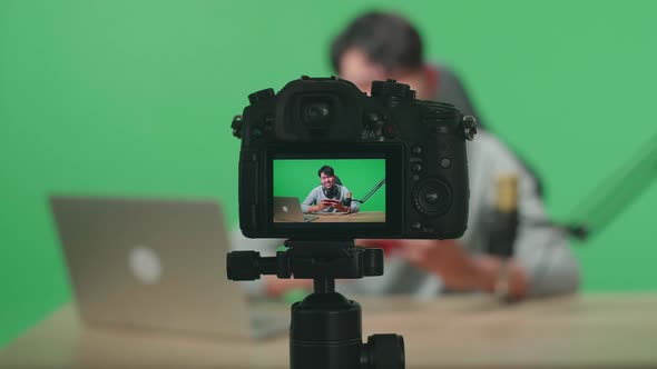 Camera Monitor of Man Reading Comment On Laptop While Playing Game On Mobile Phone On Green Screen