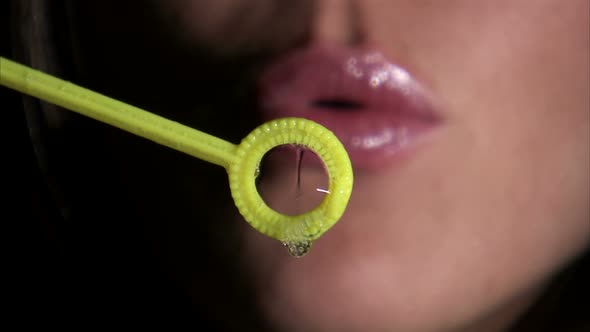 Close-up of a girl blowing bubbles towards the camera.