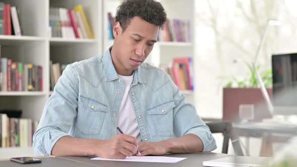 Stressed Young African American Man Failing to Write on Paper
